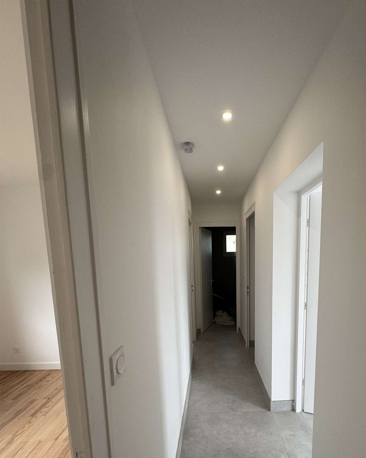 Couloir de logement terminé, spots allumés en enfilade et interrupteur posé