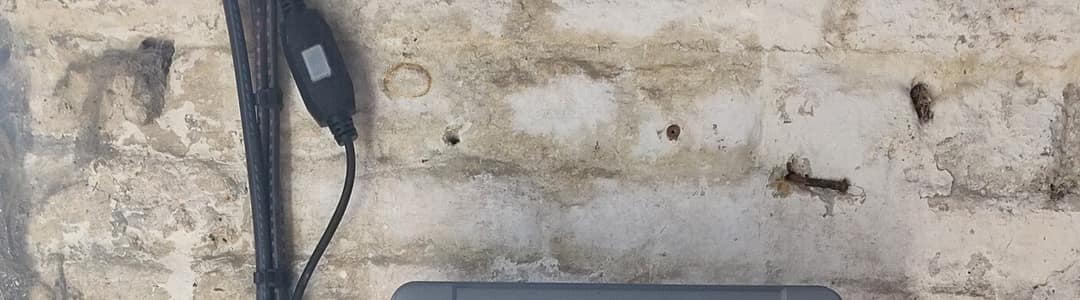 Mur de moellons enduit à la chaux d’un bâtiment ancien, câble électrique en applique